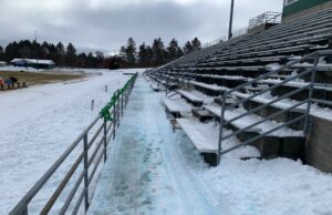 Snow covered the bleachers and field before Saturday's game.
